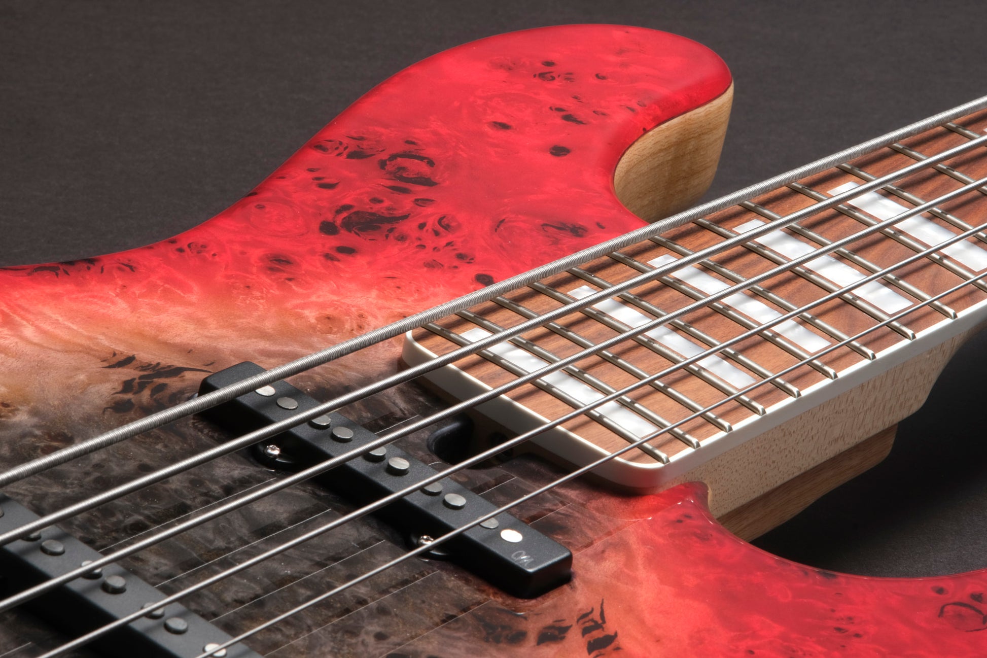Close-up of a red electric bass guitar with a dark background