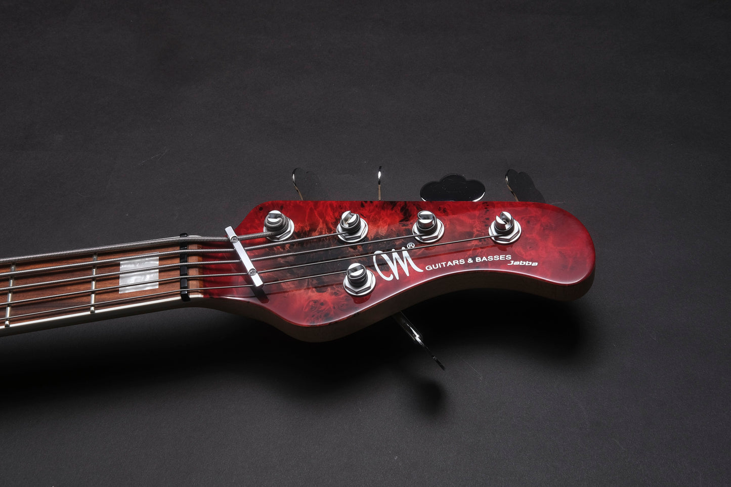 Close-up of a red electric guitar headstock on a dark background