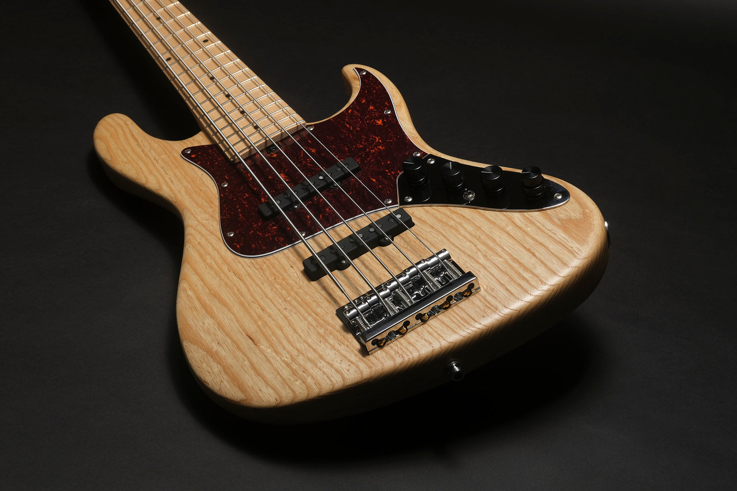 Close-up of a bass guitar with a wooden body on a dark background