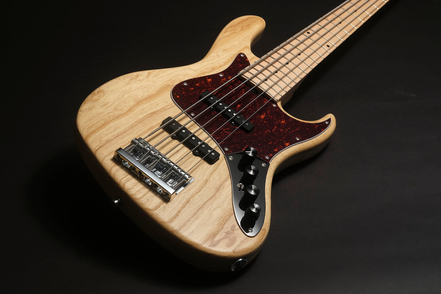 Electric bass guitar with a wooden finish on a black background