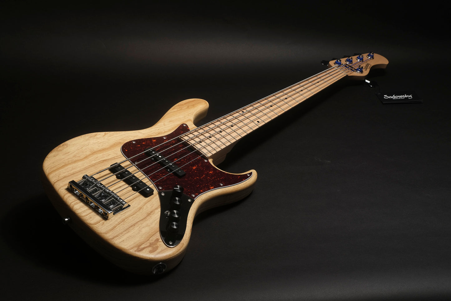 Electric bass guitar with a wooden finish on a black background