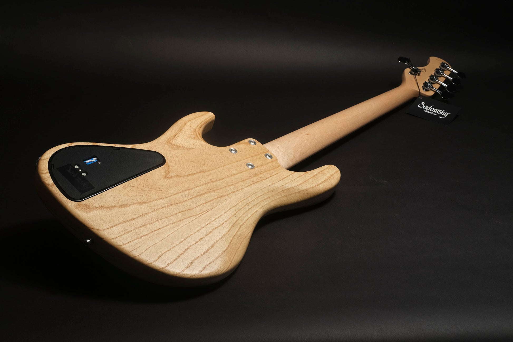 Electric bass guitar with a wooden finish on a black background