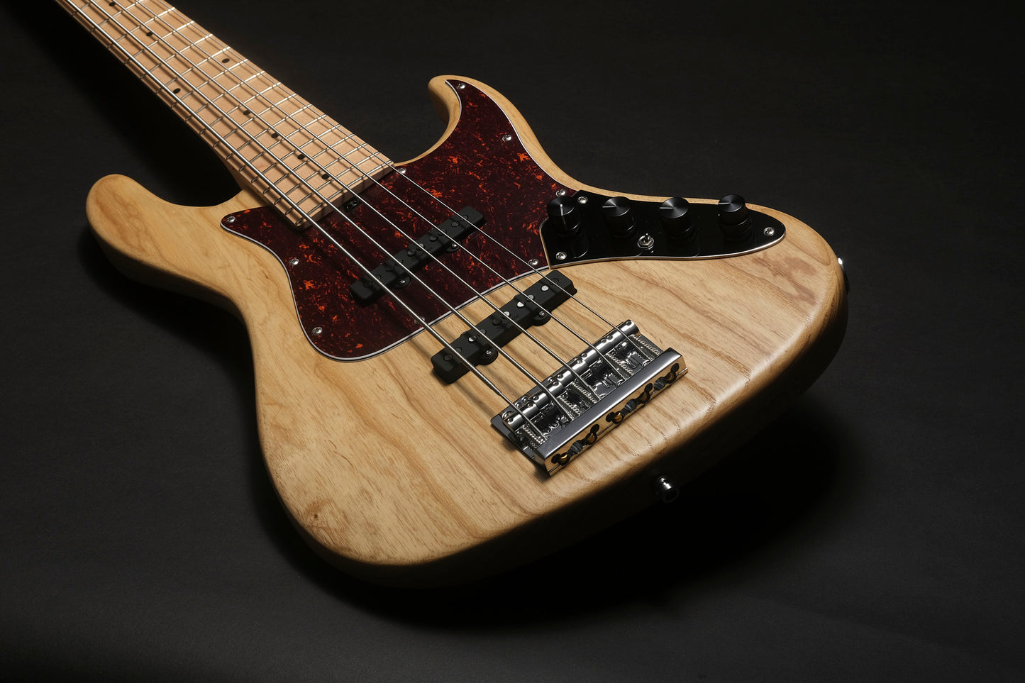 Electric bass guitar with a wooden body on a black background