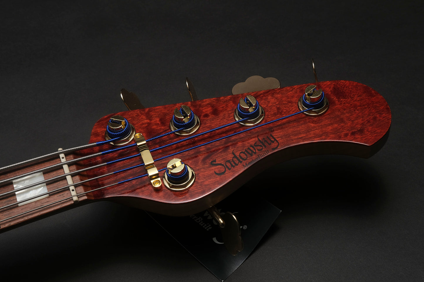 Close-up of a guitar headstock with 'Sadowsky' branding on a dark background