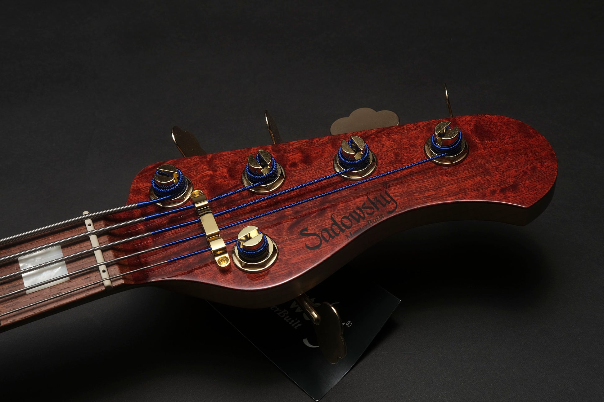 Close-up of a guitar headstock with 'Sadowsky' branding on a dark background