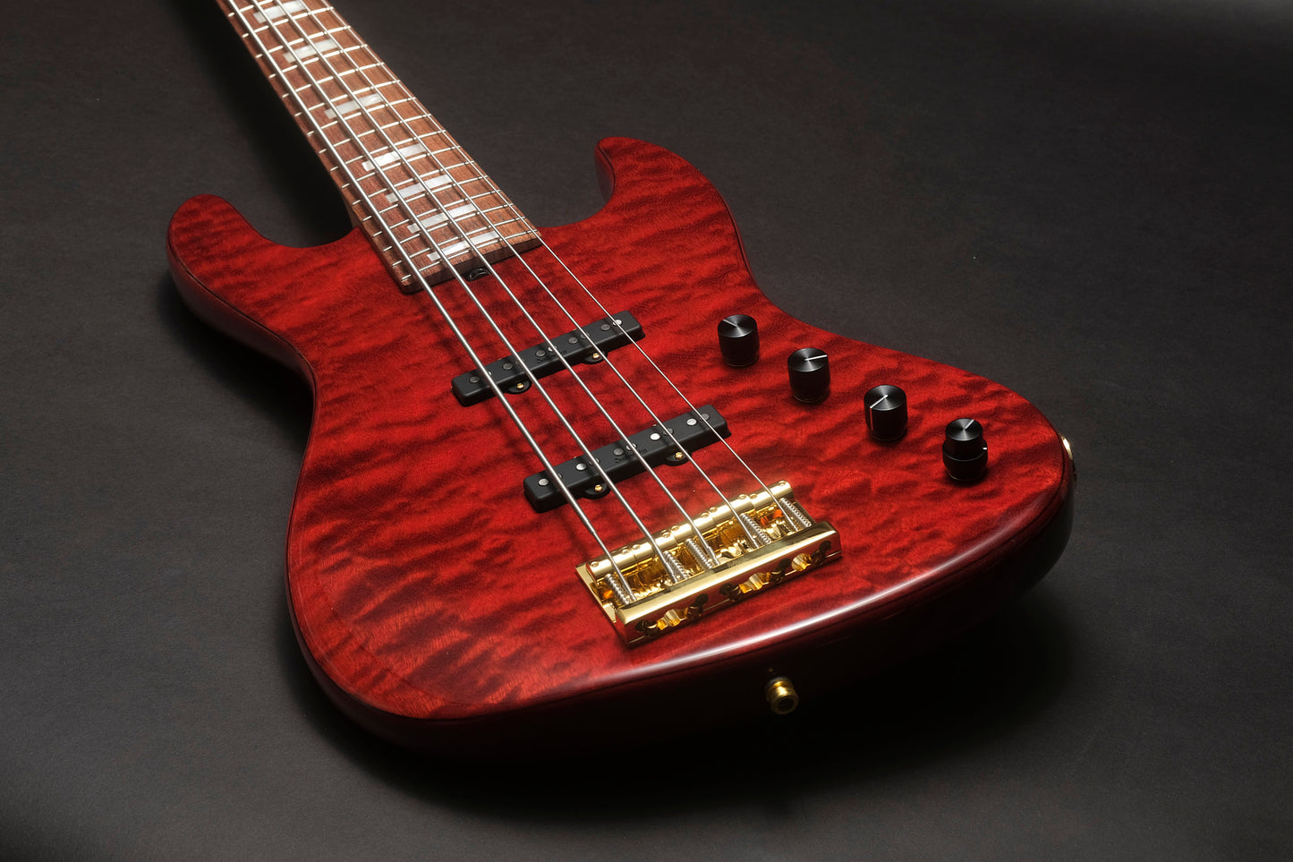Red electric bass guitar with a gold bridge on a dark background